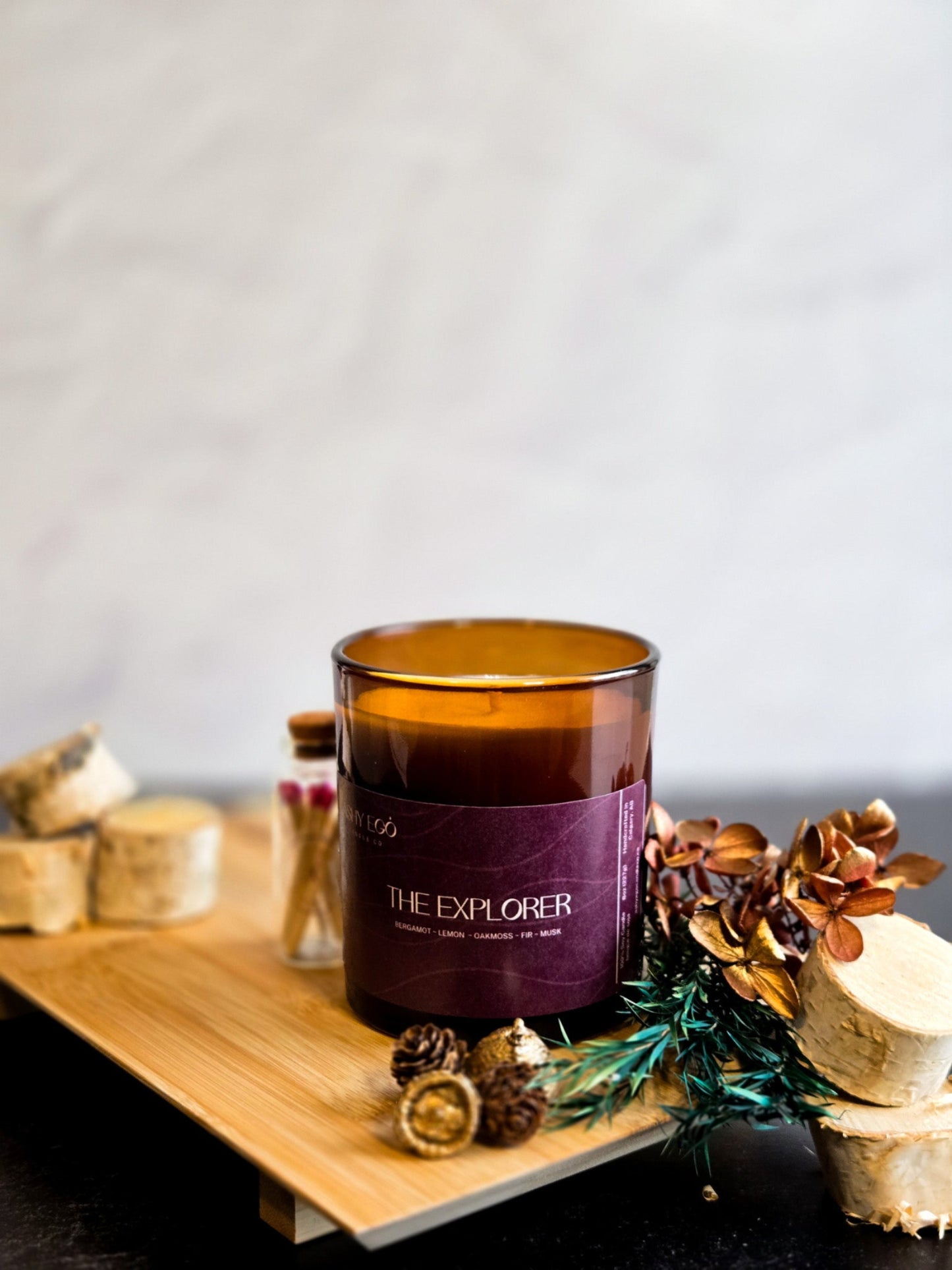 Candle labeled 'The Explorer' on a wooden surface with decorative elements.